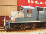 Left side of cab, showing the Cannon brake chain tensioner and cab mirror, the latter made from a cut-down mirror P2K GP38-2 mirror.  Also visible to the left of the dampening strut on the center axle is a brake cylinder mounting plate, a reminder of the days when these units were ordered new by Reserve Mining with three brake cylinders per truck.